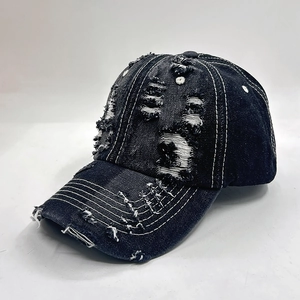 Detail of distressed denim baseball cap featuring white contrast stitching and torn fabric