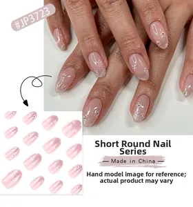 Detail of short round press-on nails with pink glitter gradient and flower accents