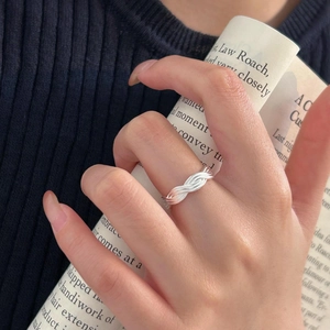 Detail of a 925 sterling silver twisted braided ring worn by a model holding a magazine