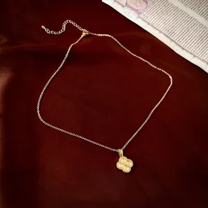 Collier élégant en or avec pendentif trèfle sur un fond en velours rouge foncé