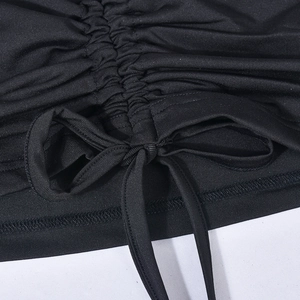 Detail of black drawstring crop top featuring ruched texture and front tie knot design