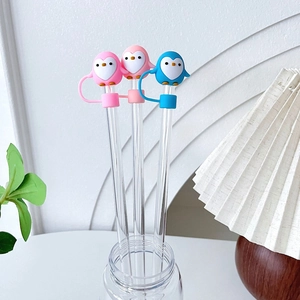 Top view of pink and blue cartoon penguin silicone straw covers on glass straws