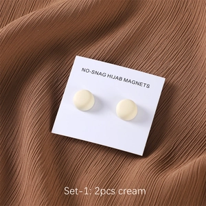 Macro detail of two cream no-snag magnetic hijab pins on white display card packaging