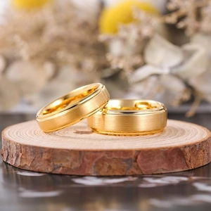 Minimalist matte brushed gold wedding rings displayed on a rustic wood slice base