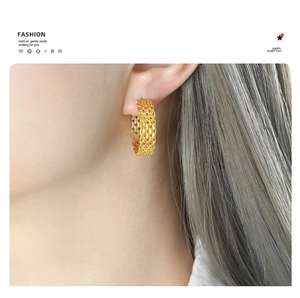 Macro view of gold-plated woven texture earrings worn on a model with a fashion aesthetic