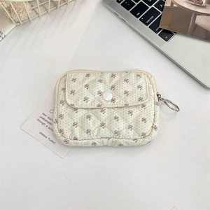 Detailed macro view of cream quilted floral pouch with snap button and metal zipper