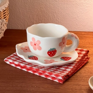 Detailed view of handmade ceramic cup and saucer set with floral and strawberry hand-painting
