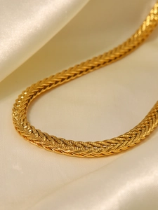 Vista dettagliata della collana intrecciata placcata oro 18K su seta beige lussuosa