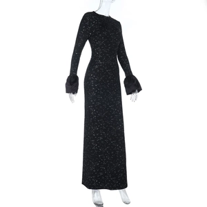 Détail d'une robe de soirée noire à paillettes, manches longues et tissu scintillant