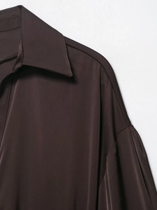 Detailed close-up of dark brown satin shirt featuring a lapel collar and smooth silk texture