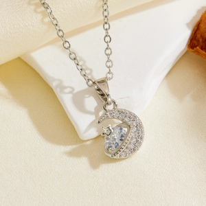 Detailed view of silver moon and star pendant with white zircon on marble and silk