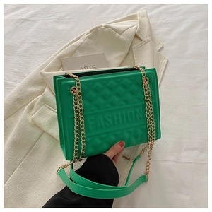 Close-up of green quilted shoulder bag with gold chain and embossed FASHION text
