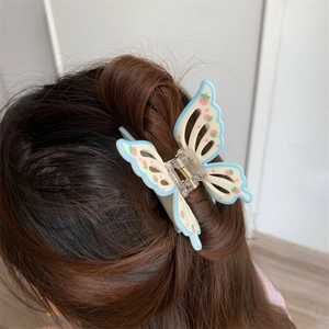 Detail of blue butterfly hair claw clip with strawberry pattern on model back of head