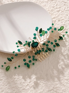 Detail of handmade gold leaf hair comb with green crystals and sparkling emerald teardrop