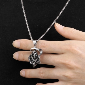 Gros plan d'un pendentif faucheuse punk argenté avec faux sur une chaîne en acier