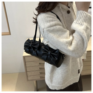 Side view of a black cylindrical pillow bag featuring large decorative bows and slim strap