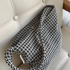 Detailed view of houndstooth knit fabric texture and 'simple wish' woven label on bag