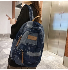 Detail view of retro patchwork denim backpack with contrast stitching and leather zipper pulls