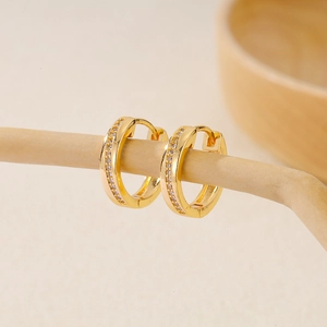 Detail of gold-plated hoop earrings with micro-set zircon rows on a wooden stand