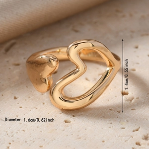 Close-up of golden heart open ring with dimension labels on textured stone surface