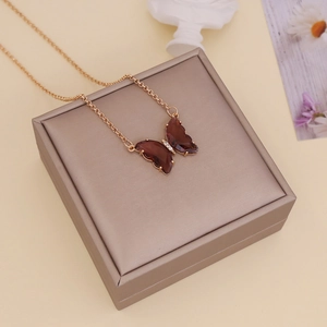 Detail view of a golden chain necklace with a brown amber butterfly glass pendant on box