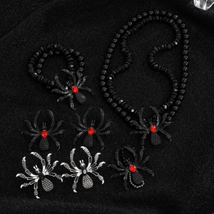 Macro shot of spider jewelry set with red crystals on a shimmering black background