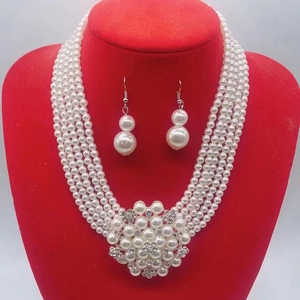 Macro view of multi-layer white pearl necklace with rhinestone flower and matching earrings