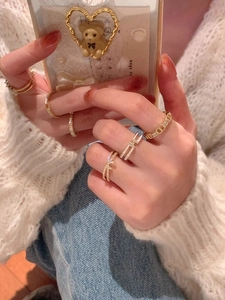 Close-up of elegant gold bow ring and layered H-design diamond ring on model's hand