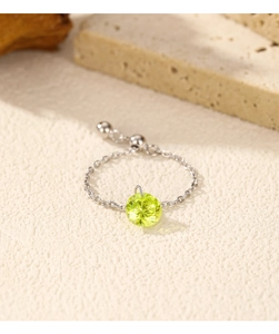 Adjustable silver chain ring featuring a round yellowish-green gemstone on a textured surface