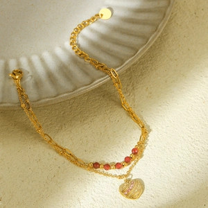 Detail of gold double-layer heart bracelet with red beads and pink crystals