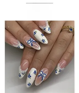 Detail of French almond nails with blueberry bow patterns and pearl accents on hand