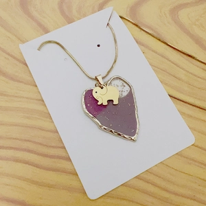 Detail of gold snake chain with purple heart pendant and small elephant charm