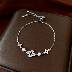 Close-up of adjustable silver bracelet with zircon clover, pearls and box chain detail