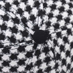 Close-up of the black and white houndstooth wool fabric and top button on the baseball cap