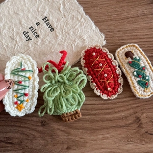 Detailed macro view of handmade crochet Christmas tree hair clips on a wood surface
