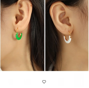 Detail of U-shaped gold-plated earrings with emerald green and cream white enamel finish