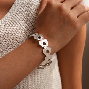 Dettaglio del bracciale argento con trama a cuore traforato e finitura metallica martellata