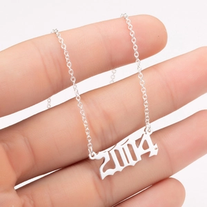 Close-up of a silver stainless steel necklace with a 2004 birth year gothic pendant