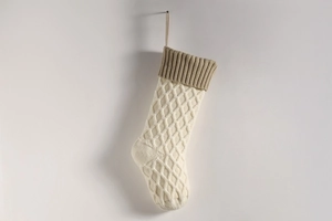 Detail der cremefarbenen Strick-Weihnachtssocke mit khakifarbenem Bündchen und Karomuster