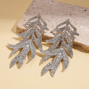 Macro d'oreilles en forme de feuille argentée avec strass sur pierre beige