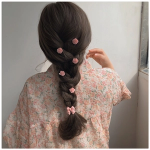 Detail of pink camellia resin hair clips and bow accessory styled in a braid
