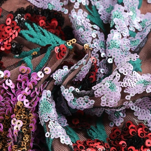 Détail macro du tissu de robe dos nu avec paillettes colorées et broderie de feuilles vertes