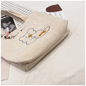Detail of corduroy tote bag with bear embroidery and decorative cow keychain