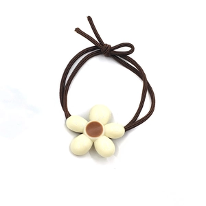 Detail view of coffee brown elastic hair tie with cream resin flower ornament