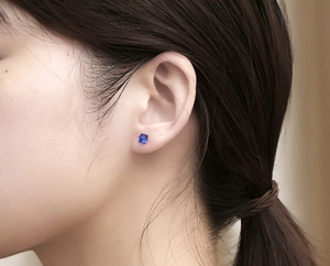 Close-up of minimalist square blue crystal stud earring worn by model in cool style