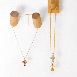 Detail of layered gold necklaces with colorful zircon cross and religious coin pendants