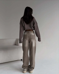Détail du jean taille haute à jambe large avec délavage vintage et pull en maille marron