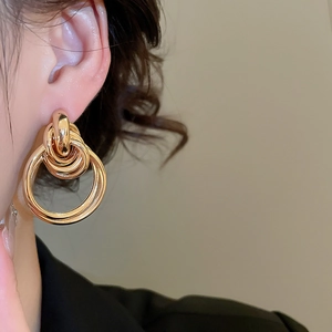 Détail de boucles d'oreilles dorées multicouches avec plusieurs anneaux entrelacés