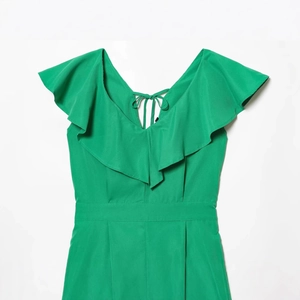 Green V-neck romper with ruffle trim and back tie detail on white background