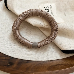 Close-up of a brown satin pleated hair tie with a matching resin buckle on wood